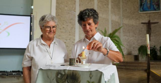 Claire Castaing, RSCJ (right), stands with current Superior General Barbara Dawson, RSCJ,  and lights Sophie's candle. This candle was at Sophie’s bedside at the time of her death; and the Society has kept it since then. Each new superior general, at the time of her election, lights this candle for a brief moment.