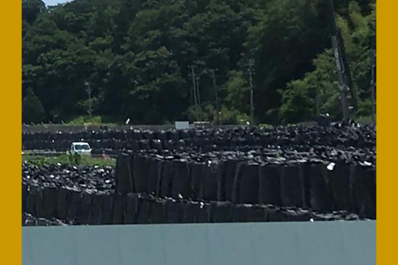Piles de sacs noirs remplis de déchets et de sols contaminés par la radioactivité, s’étendant à perte de vue.